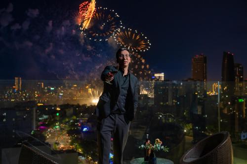 a man standing on top of a building with fireworks at Rest Hotel & Apartment in Da Nang