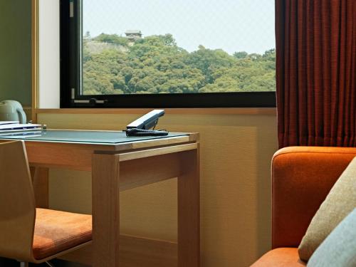 a desk with a laptop on it next to a window at Candeo Hotels Matsuyama Okaido in Matsuyama