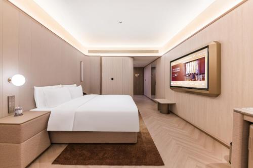 a hotel room with a white bed and a tv at Crystal Hotel Guangzhou Huadu in Huadu