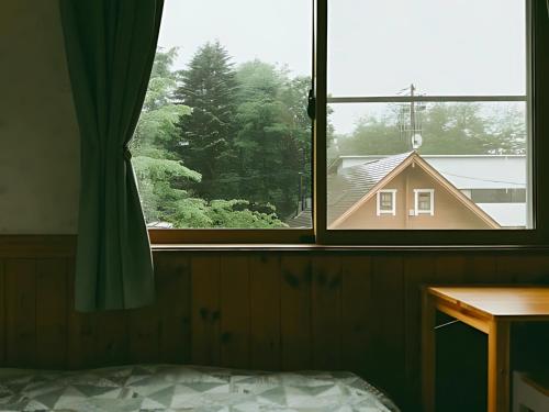 a bedroom with a window with a view of a house at Guest House Chaconne Karuizawa in Karuizawa