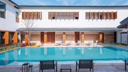 a swimming pool with chairs and a building at Meijie Xiuju in Xinchating