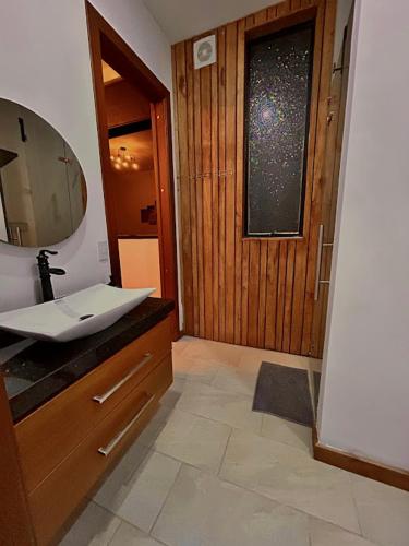 a bathroom with a sink and a wooden door at Casa Fénix Zen Oasis Del Bosque in Calima