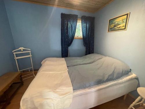 a bedroom with a bed and a window with blue walls at Peaceful Cabin near Furufjall Trail in Spekeröd