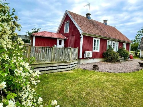 a red house with a wooden fence in the yard at 4 star holiday home in KÖPINGSVIK in Köpingsvik