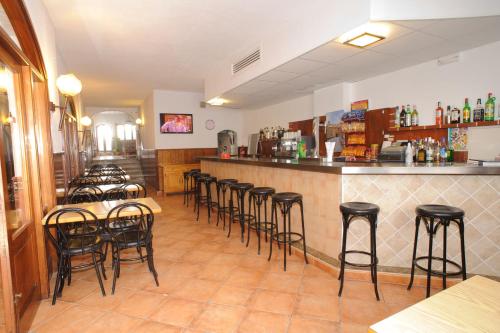 un restaurant avec une rangée de tabourets au bar dans l'établissement Hostal Montaña, à Sant Antoni de Portmany
