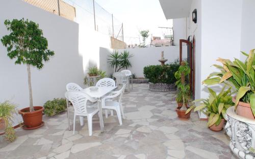 d'une terrasse avec des tables et des chaises blanches et des plantes en pot. dans l'établissement Hostal Montaña, à Sant Antoni de Portmany