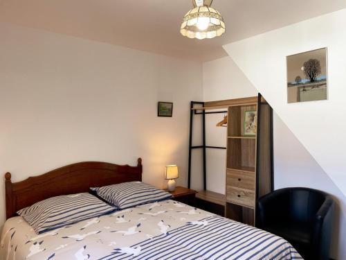 a bedroom with a bed and a black chair at La Grange: Gîte Confort à Briou, 5 Chambres - FR-1-491-471 