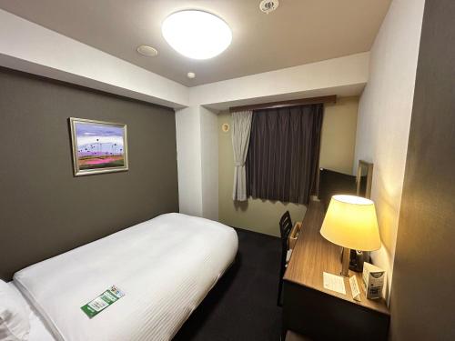 a hotel room with a bed and a desk with a lamp at Hotel Route-Inn Itoigawa in Itoigawa