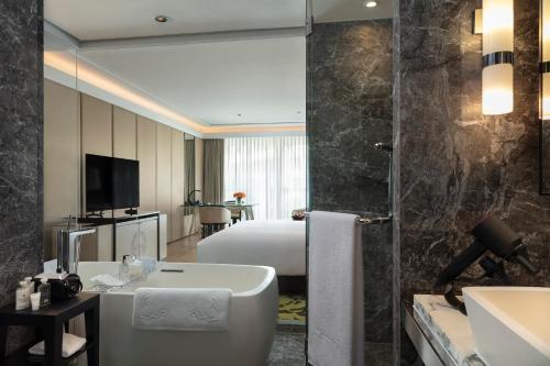 a hotel bathroom with a tub and a bedroom at Siam Kempinski Hotel Bangkok in Bangkok