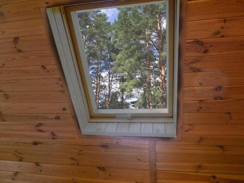 a window in a room with a wooden wall at at the lake with a boat in Spychowo