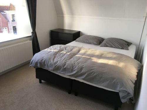 ein Bett in einem Schlafzimmer mit Fenster in der Unterkunft Holiday apartment in Alkmaar in Alkmaar