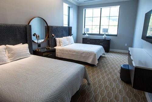 a hotel room with two beds and a mirror at The Schoolhouse Hotel, Trademark Collection by Wyndham in White Sulphur Springs