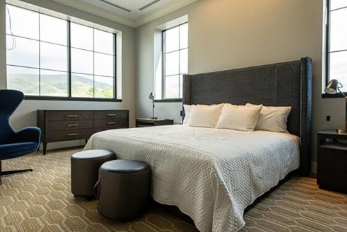 a bedroom with a bed and a chair and windows at The Schoolhouse Hotel, Trademark Collection by Wyndham in White Sulphur Springs