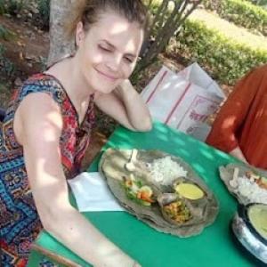 a woman sitting at a table with a plate of food at An Authentic Village Farm in Jhānsi