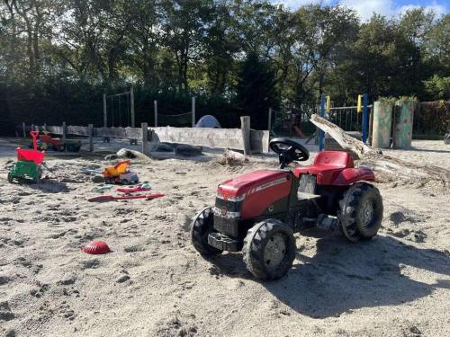 a small red toy tractor in the sand at Holiday home with 2 bedrooms in Zwiggelte
