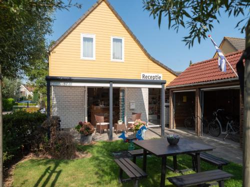 a house extension with a table in the yard at Holiday Home in Quiet Park with Garden in Wemeldinge