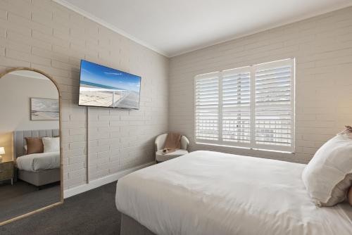 a white bedroom with a bed and a window at Bright 2-Bed Apartment Steps from Largs Bay Beach in Largs