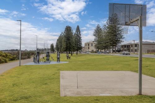 a park with a basketball hoop in the grass at Bright 2-Bed Apartment Steps from Largs Bay Beach in Largs