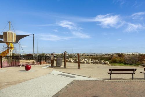 a park with two benches and a windmill at Bright 2-Bed Apartment Steps from Largs Bay Beach in Largs
