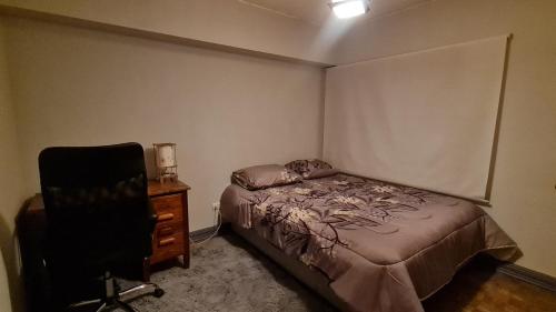 una camera con letto, sedia e cassettiera di Habitación céntrica a Santiago
