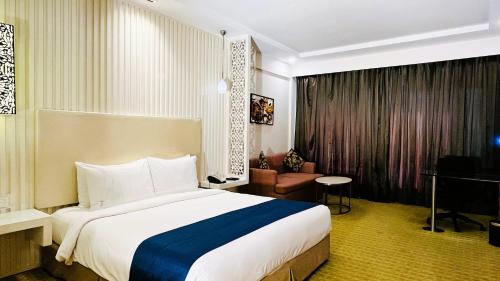 a hotel room with a large bed and a chair at Holiday Inn Amritsar Ranjit Avenue by IHG in Amritsar