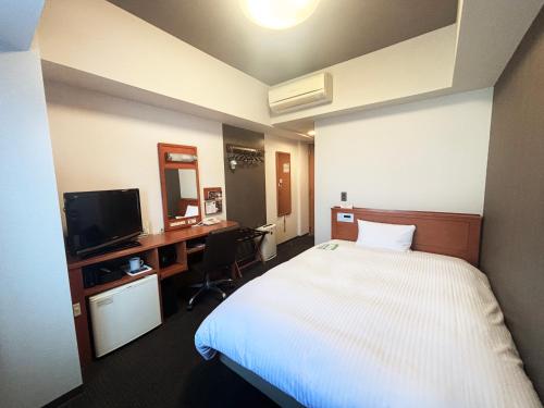 una camera d'albergo con un letto e una scrivania con un computer di Hotel Route-Inn Suzuka a Suzuka