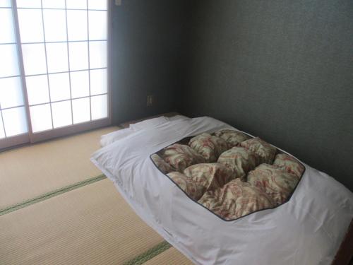 a bed with a blanket on it in a room at Hotel Sankyu in Tsukuba