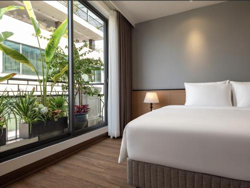 a bedroom with a bed and a large window at Minasi Grand Hotel in Hanoi