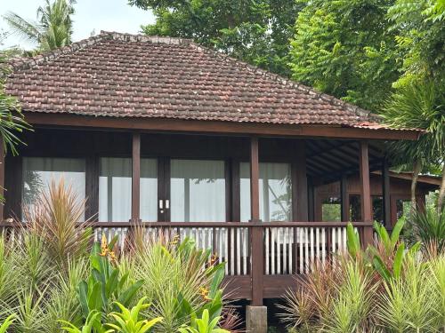 a house with a wooden porch with windows at Melaya Cabanas in Candikesuma