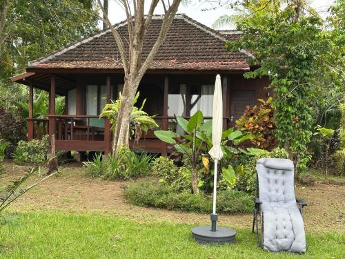 a umbrella and a chair in front of a house at Melaya Cabanas in Candikesuma