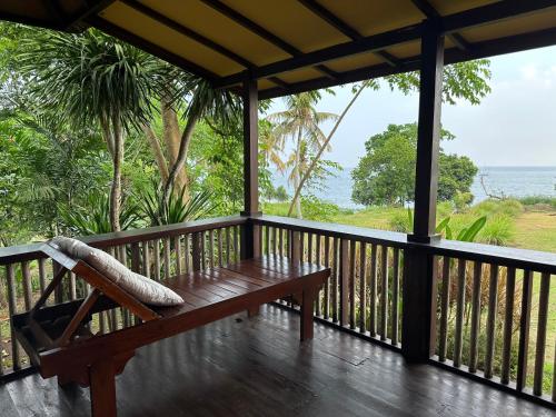 a wooden porch with a bench on a deck at Melaya Cabanas in Candikesuma