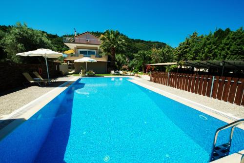 a swimming pool with blue water in front of a house at Villa Verde in Lefkada Town