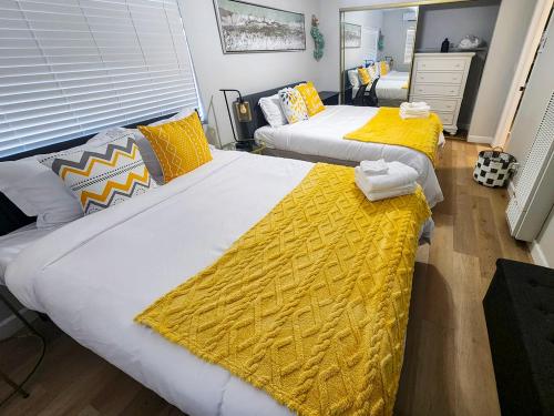 two beds in a room with yellow and white sheets at Relaxing Cozy Back House with Backyard in Upland