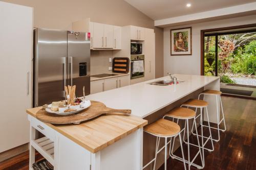 a kitchen with a stainless steel refrigerator and stools at Port Douglas Alamanda Estate w Ocean Views & Pool in Craiglie