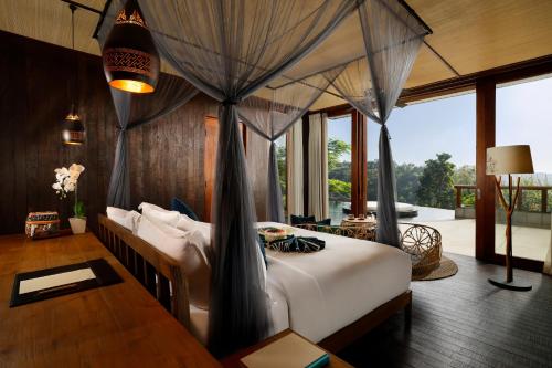 a bedroom with a bed in a room with a table at Akohara Buahan Village Retreat in Payangan