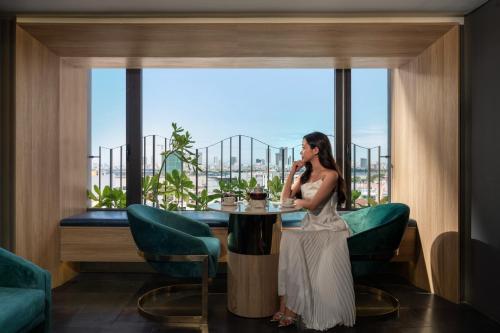a woman sitting at a table talking on a cell phone at Rest Hotel & Apartment in Da Nang
