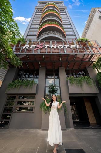 a woman in a white dress standing in front of a building at Rest Hotel & Apartment in Da Nang