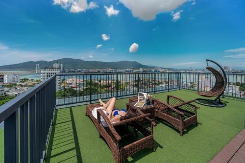 a woman laying in chairs on a balcony at Rest Hotel & Apartment in Da Nang