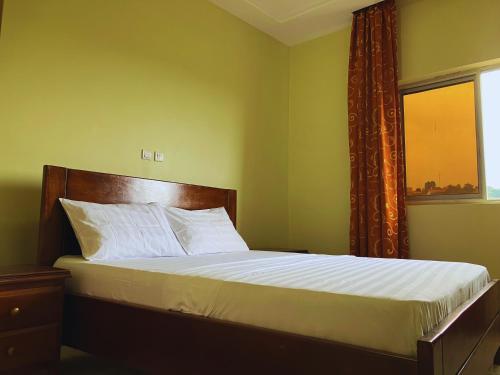 a bed in a room with a window and a bedvisor at Résidence Romacy, appartement 2 chambres avec balcon à Ahala, quartier résidentiel de Yaoundé in Yaoundé