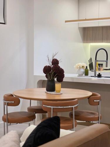a dining room table with a vase of flowers on it at 'CoCo' 2-BR Apt in the heart of Burwood with free parking in Sydney