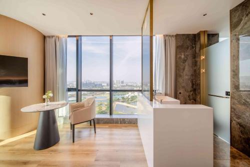 ShundeBodun International Apartment Foshan Shunde Fengjian Water Village Branch的厨房以及带桌子和大窗户的用餐室。