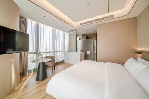 a hotel room with a large white bed and a table at Bodun International Apartment Foshan Shunde Fengjian Water Village Branch in Shunde