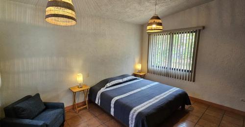 1 dormitorio con 1 cama, 1 silla y 2 luces en The Weiss House - Mountain, Pool and Rest, en Tepoztlán