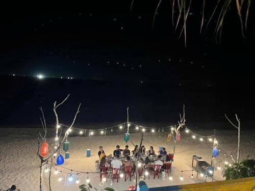 a group of people sitting at a table on the beach at night at Homestay Thiện Nhân 