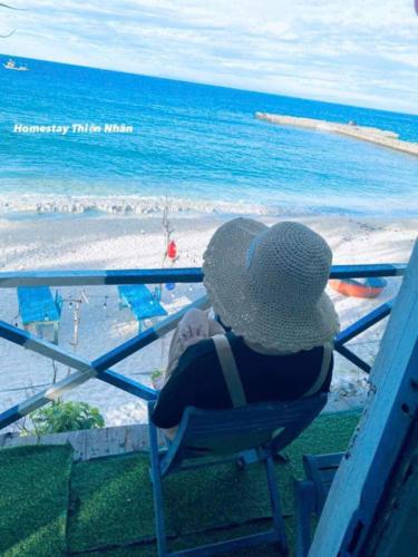 a person sitting in a chair looking at the beach at Homestay Thiện Nhân 