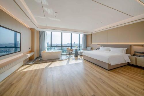 ShundeBodun International Apartment Foshan Shunde Fengjian Water Village Branch的一间卧室设有一张床、浴缸和一个窗口