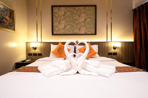 a bed with two white towels in the shape of a heart at Baan Sukhumvit Soi 20 in Bangkok