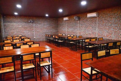 a room with wooden tables and chairs and a brick wall at Phúc Hưng Homestay- Venuestay in Ba Vì