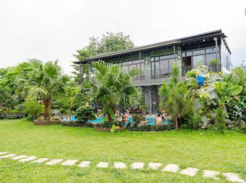 a house with a pool and people in the yard at Phúc Hưng Homestay- Venuestay in Ba Vì