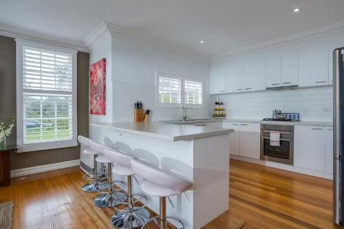 a kitchen with white cabinets and bar stools at Sorrento Darling by Ready Set Stay in Sorrento